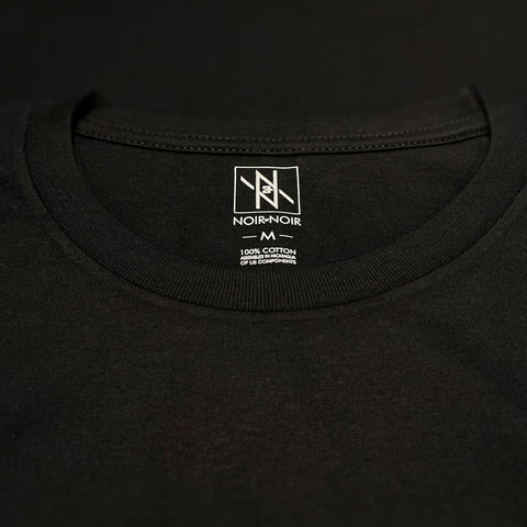 Close-up of the Noir et Noir branding label and collar detail on the Veiled Revelations unisex T-shirt, showcasing premium craftsmanship and attention to detail. Part of the elegant Design Collection.